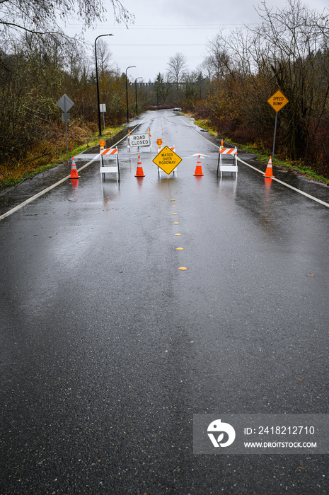 Closed road due to rainfall flooding over the roadway, barricades, empty road, stormy sky