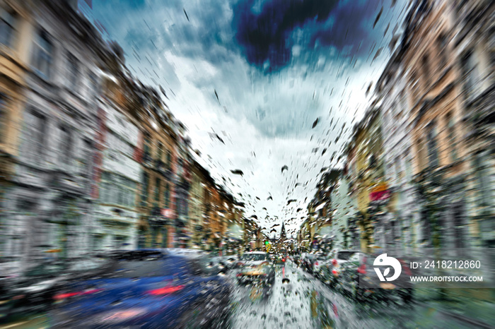 Car windshield with rain drops during storm and blurred stoplights