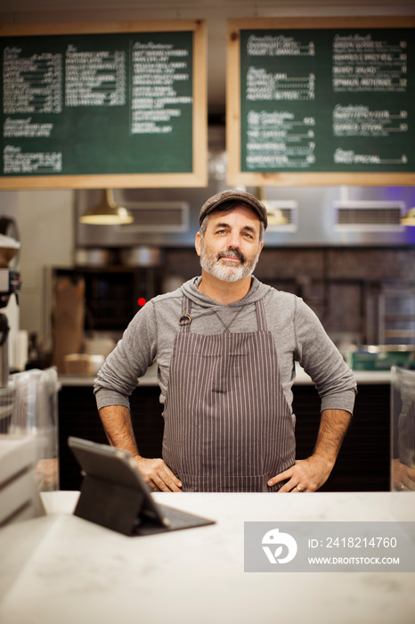 Portrait of confident male owner with tablet computer on bar counter standing in cafe