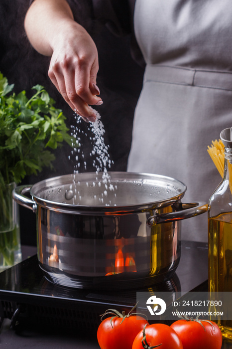 young woman in a gray apron preparing pasta