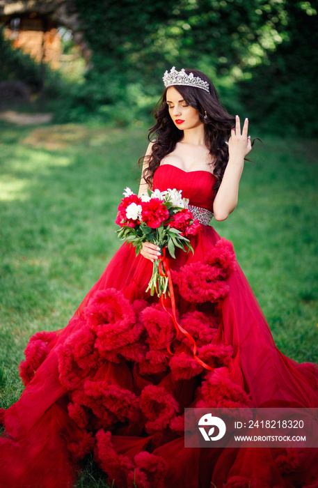 美丽的深色头发，戴着皇冠，手里拿着花束，穿着时髦的大而茂盛的红色连衣裙