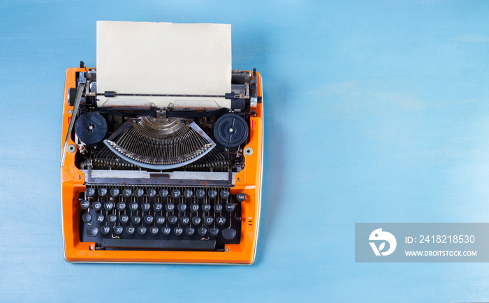 蓝色木桌背景上有橙色老式打字机的工作区