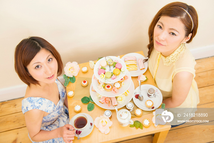 Two women looking up from their teatime treats