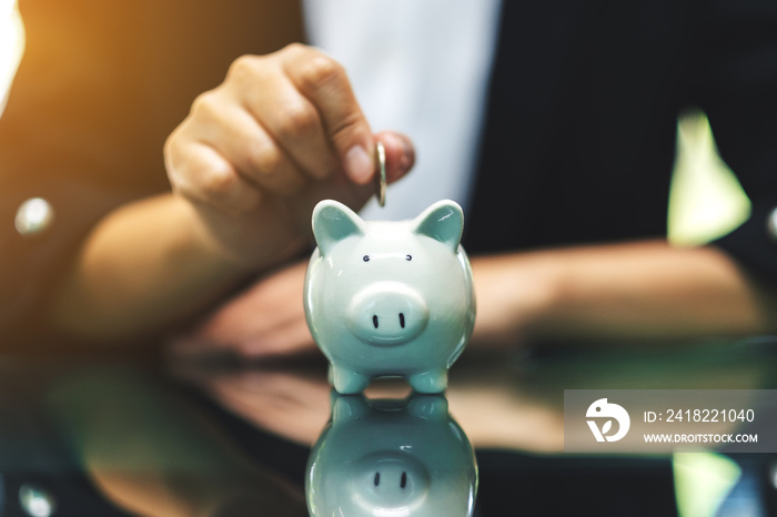 A woman putting coins into piggy bank for saving money concept