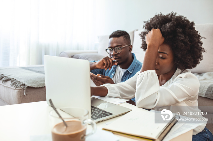 Stressed unhappy couple arguing about huge expenses with laptop and papers, angry husband blaming wi