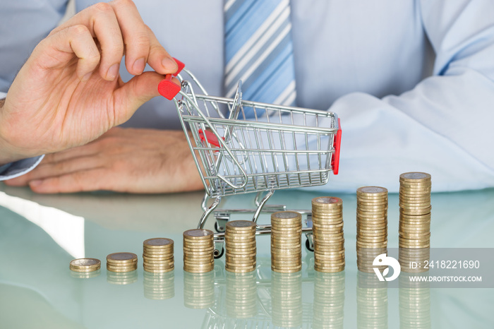 Businessman With Stacked Coins And Small Shopping Cart