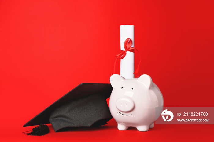 Graduation hat, piggy bank and diploma on color background