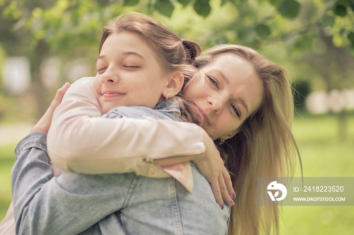 快乐的母亲和她的女儿在夏天拥抱一个青少年。关爱快乐的母亲享受一天