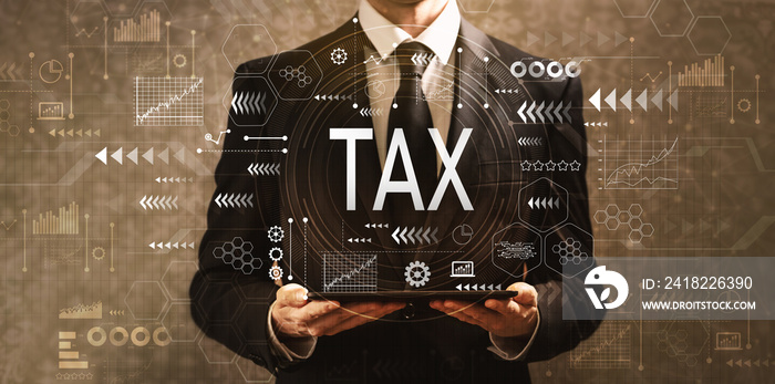 Tax with businessman holding a tablet computer on a dark vintage background