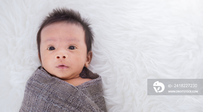 Closeup portrait of asian happy baby wrap up in gray blanket over white background with copy space, 