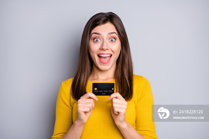 Portrait of attractive amazed cheerful girl holding in hands bank card having fun funds isolated ove