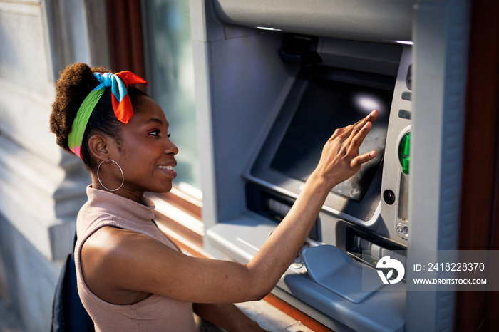 漂亮的非洲女人在使用ATM机。漂亮的年轻女人从信用卡上取钱