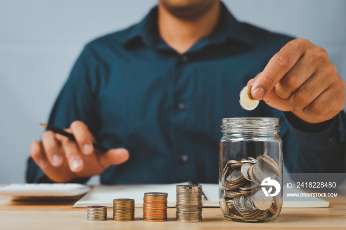 A businessman with a coin in a glass Along with pressing the calculator and write down savings for t