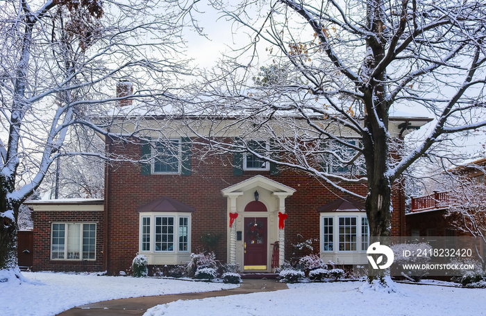 Beautiful brick house with bay windows with Christmas tree showing through and decorated pillars and