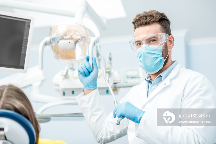 Portrait of a dentist in mask and protective glasses during the dental surgery