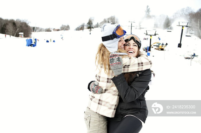 幸福的女人在白雪覆盖的山上拥抱朋友