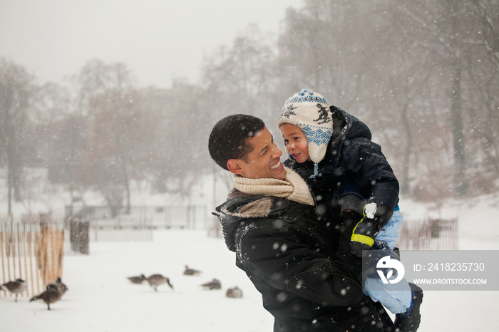 快乐的父亲在雪地上抱着儿子