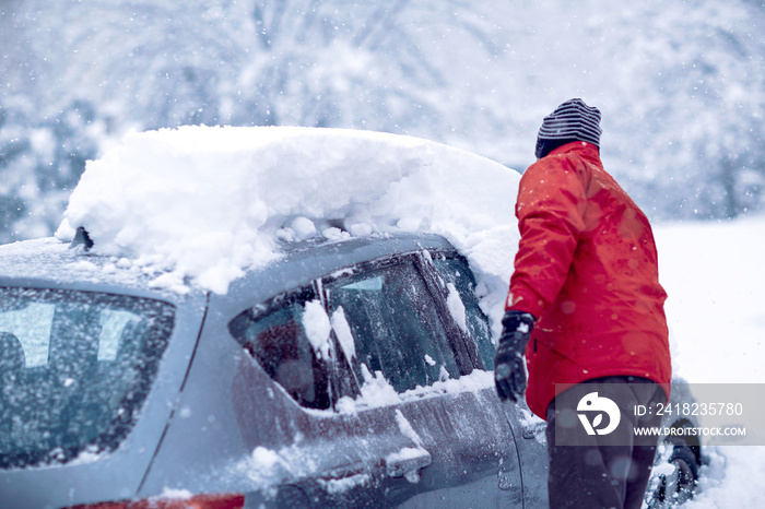 Car stuck in snow. man brushing the snow off his car on a  winter day