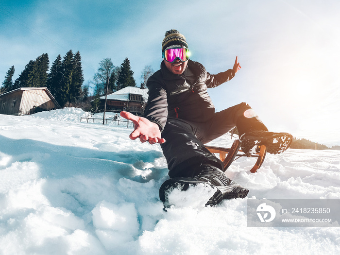 Young crazy man having fun with wood vintage sledding on snow mountain landscape - Happy guy enjoy w