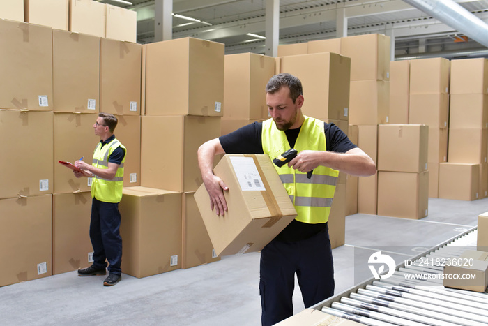 货物中的工人扫描装有货物的包裹//Arbeiter im Versand scannt ein Paket mit Waren