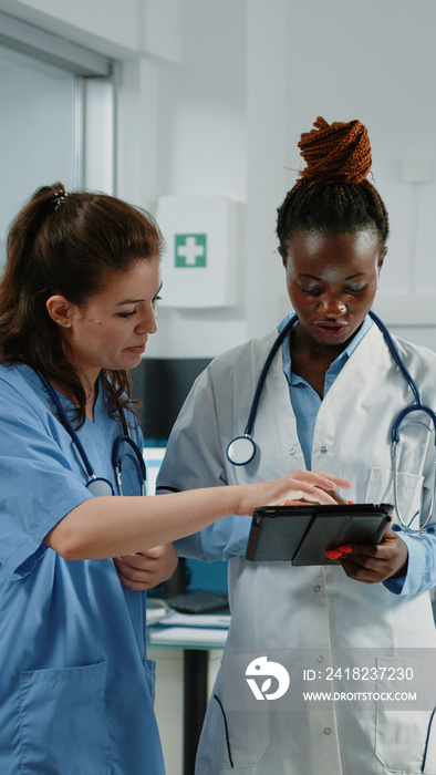 Doctor and nurse working with tablet for healthcare system in cabinet. Medical team of medic and ass