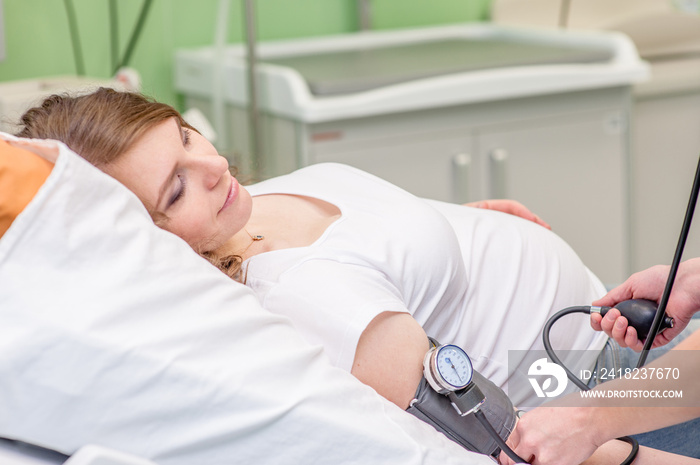 Pregnant woman having her blood pressure checked by the doctor