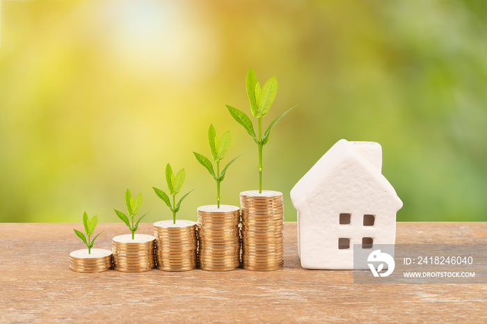 Model house and coin stack with tree on blur green background mortgage saving concept