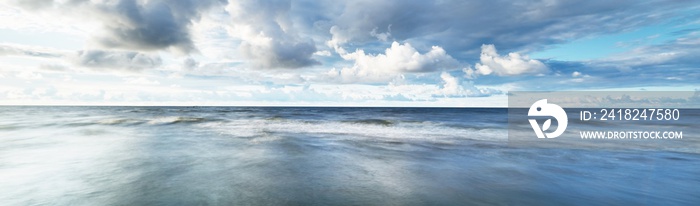 Clear sky with lots of glowing cumulus clouds above the Baltic sea shore after thunderstorm at sunse