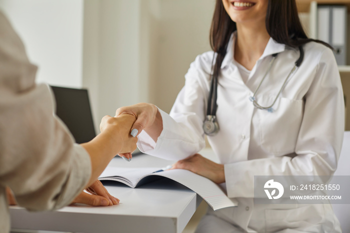 Friendly doctor reassuring her patient touching her hand gently during interview in hospital office