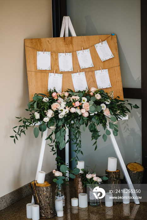 Seating of guests. Original vintage wooden board with decoration and a guest list. Tables wedding gu