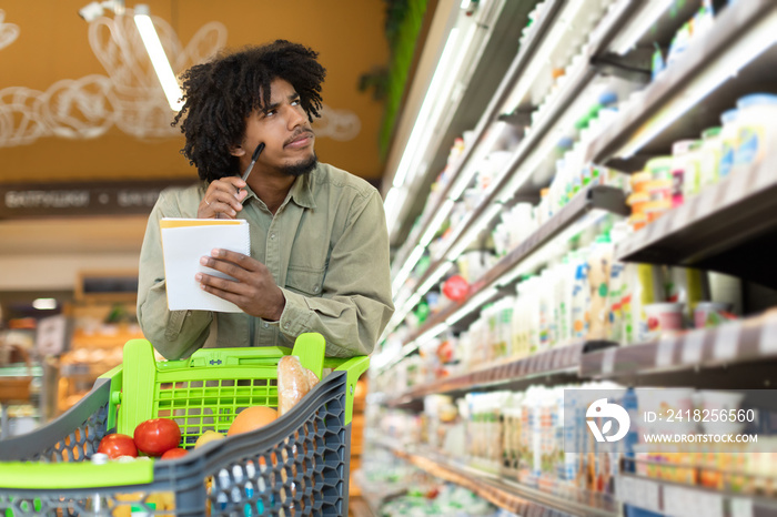 黑人拿着购物清单在超市计算食品价格