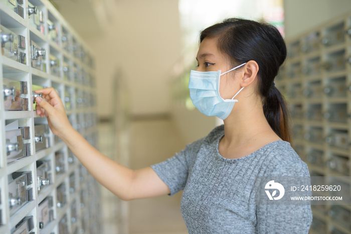 戴口罩的亚洲年轻女性查看邮箱