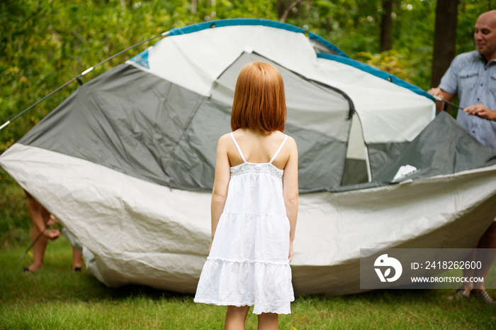 Father with daughter (6-7) folding up tent