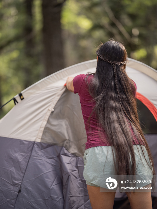 Indigenous woman closing her tent while camping