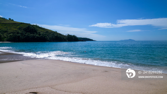 Brazilian woman in bikini on a deserted beach in Ubatuba, São Paulo, Brazil. Playing in the sea wate