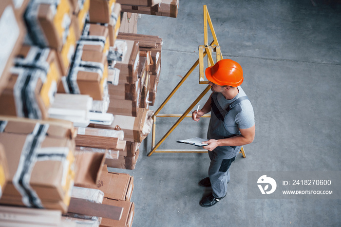 Top view of male worker in warehouse with notepad in hands