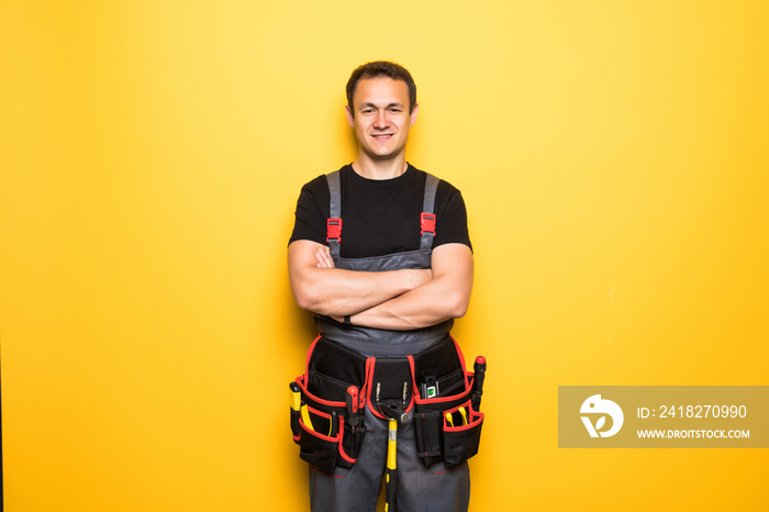 Portrait of happy handyman with tools belt isolated on yellow background