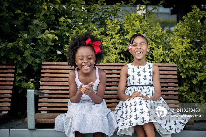 Girls laughing on bench outdoors