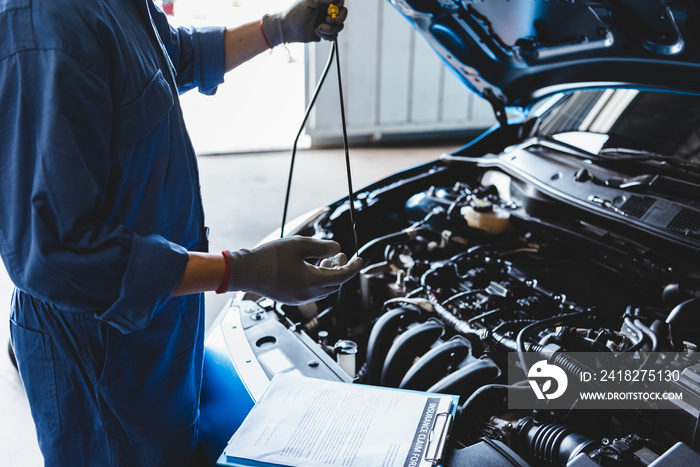汽车修理中，汽车修理工手持检查齿轮油，按客户索赔单对车辆进行维修