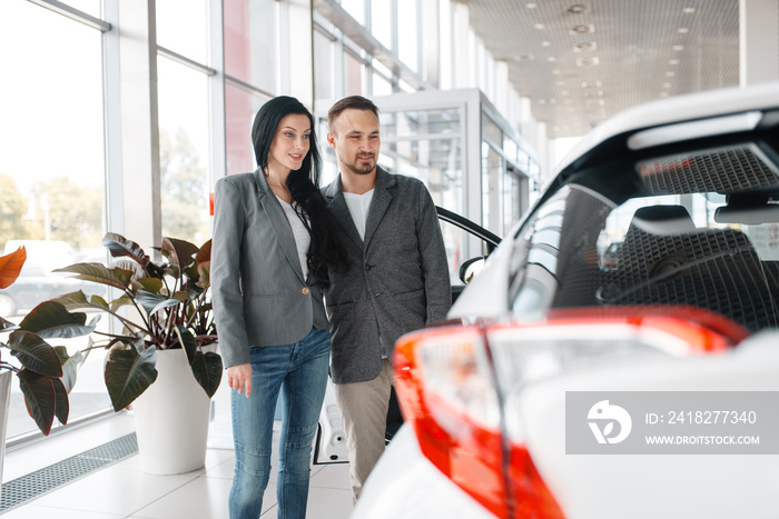 Happy couple buying new car in showroom