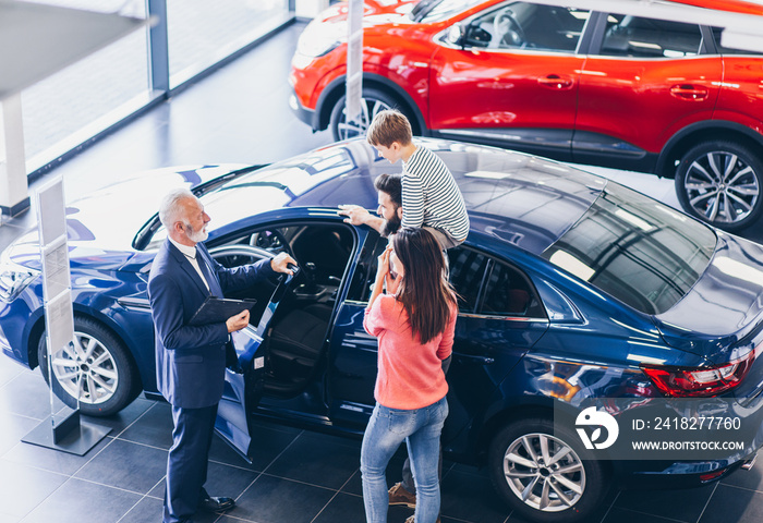 Happy family buying a new car at the car showroom.