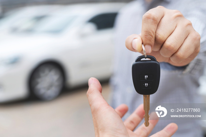 Car key, businessman handing exchange over give to the other man on showroom background. Seller deal