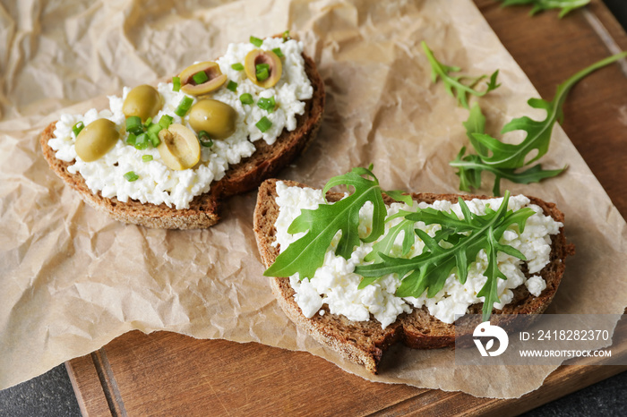 Tasty sandwiches with cottage cheese and olives on wooden background, closeup