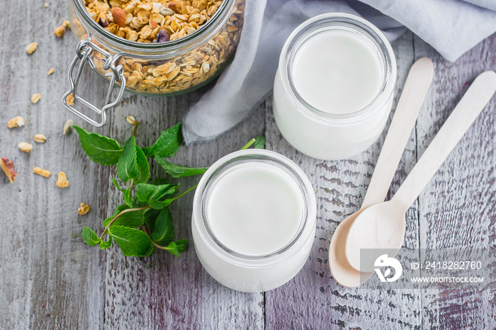 Two glass jarы with greek yogurt and jar with homemade oat granola for healthy breakfast, top view