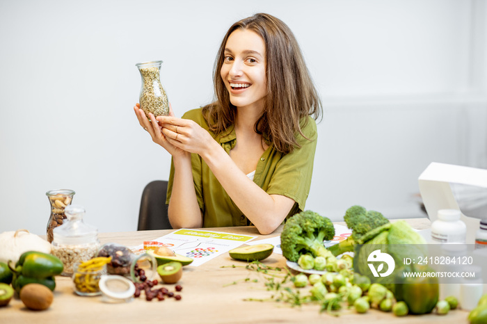 一个年轻快乐的女人的画像，桌上有大麻籽和很多健康的绿色食物。海螺