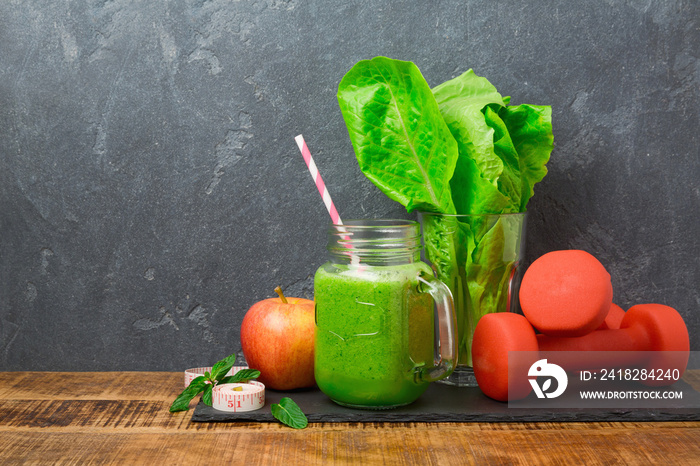 Green smoothie with apple, lettuce and dumbbells over dark background. Detox, dieting, vegetarian, f