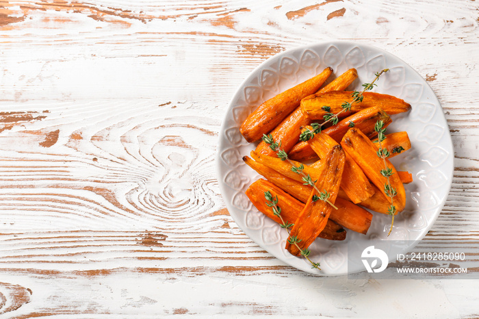 Plate with tasty cooked carrot on wooden table