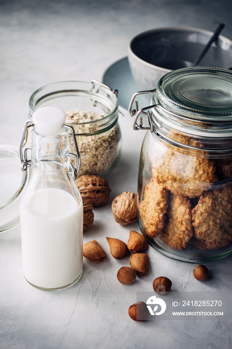 galletas de avena, copos de avena, leche, en recipientes de vidrio, con un puñado de frutos secos, u