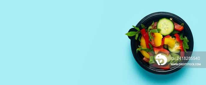 Vegetable salad in a plastic disposable bowl on a light blue background. Top view, flat lay. Banner