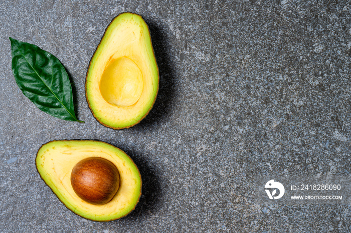 Opened avocado showing seed on textured stone background.